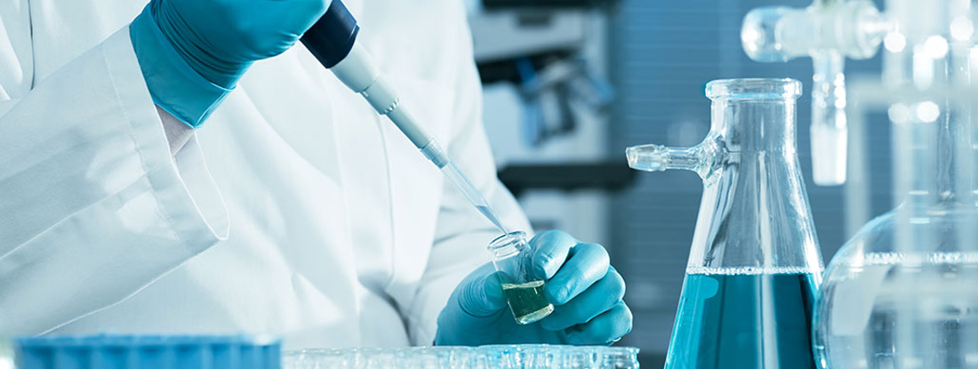 A scientist extracts blue liquid from a test tube in a medical research facility
