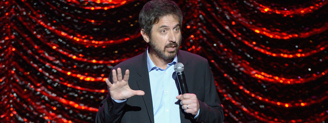 Ray Romano holds microphone on stage 