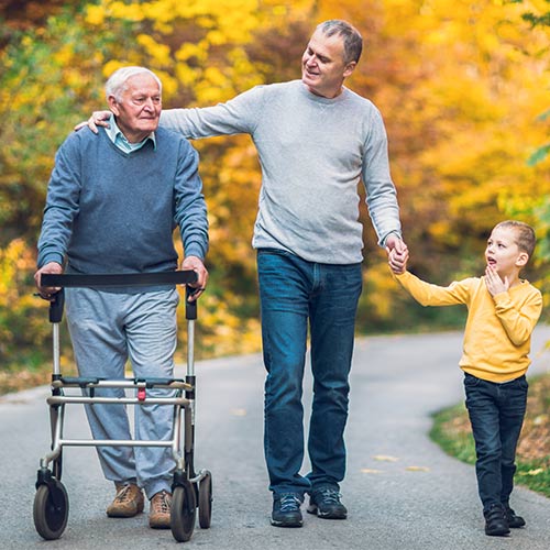elderly patient walking with the help of a walker with son and granddaughter