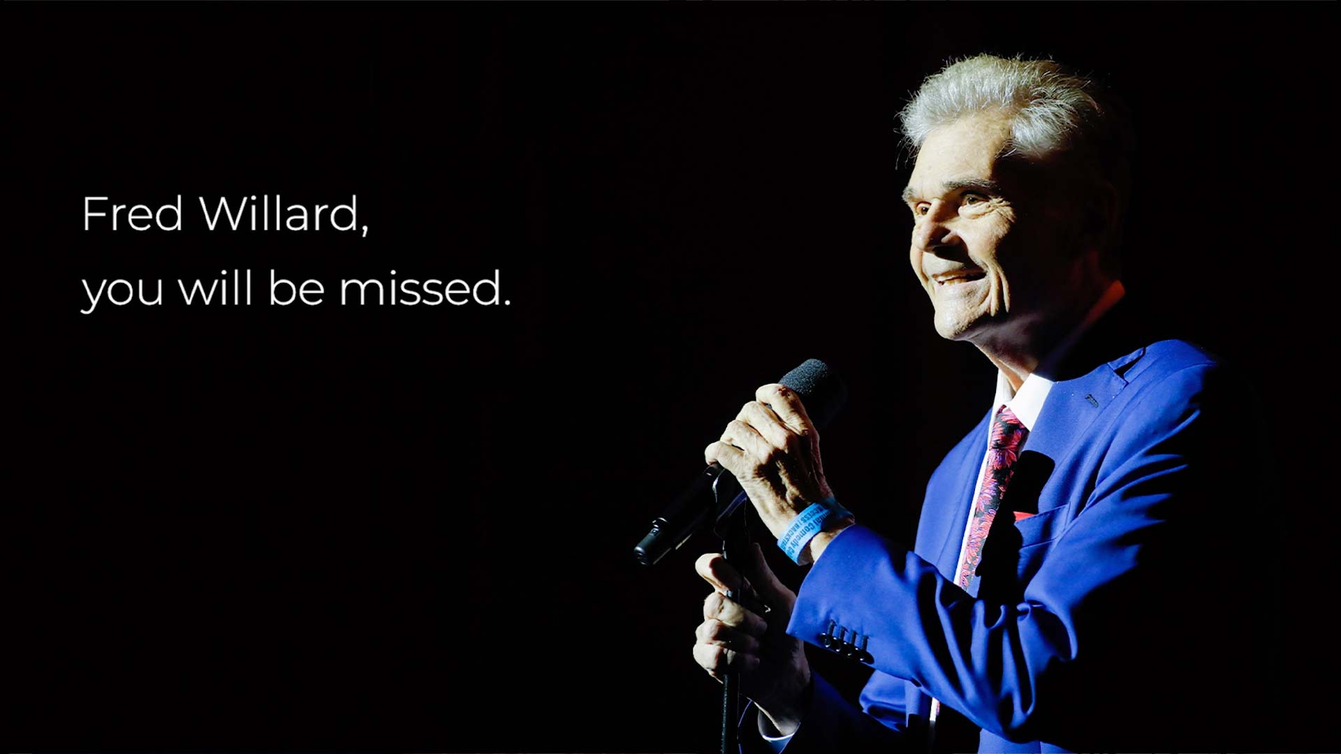 Comedian Fred Willard holds a microphone