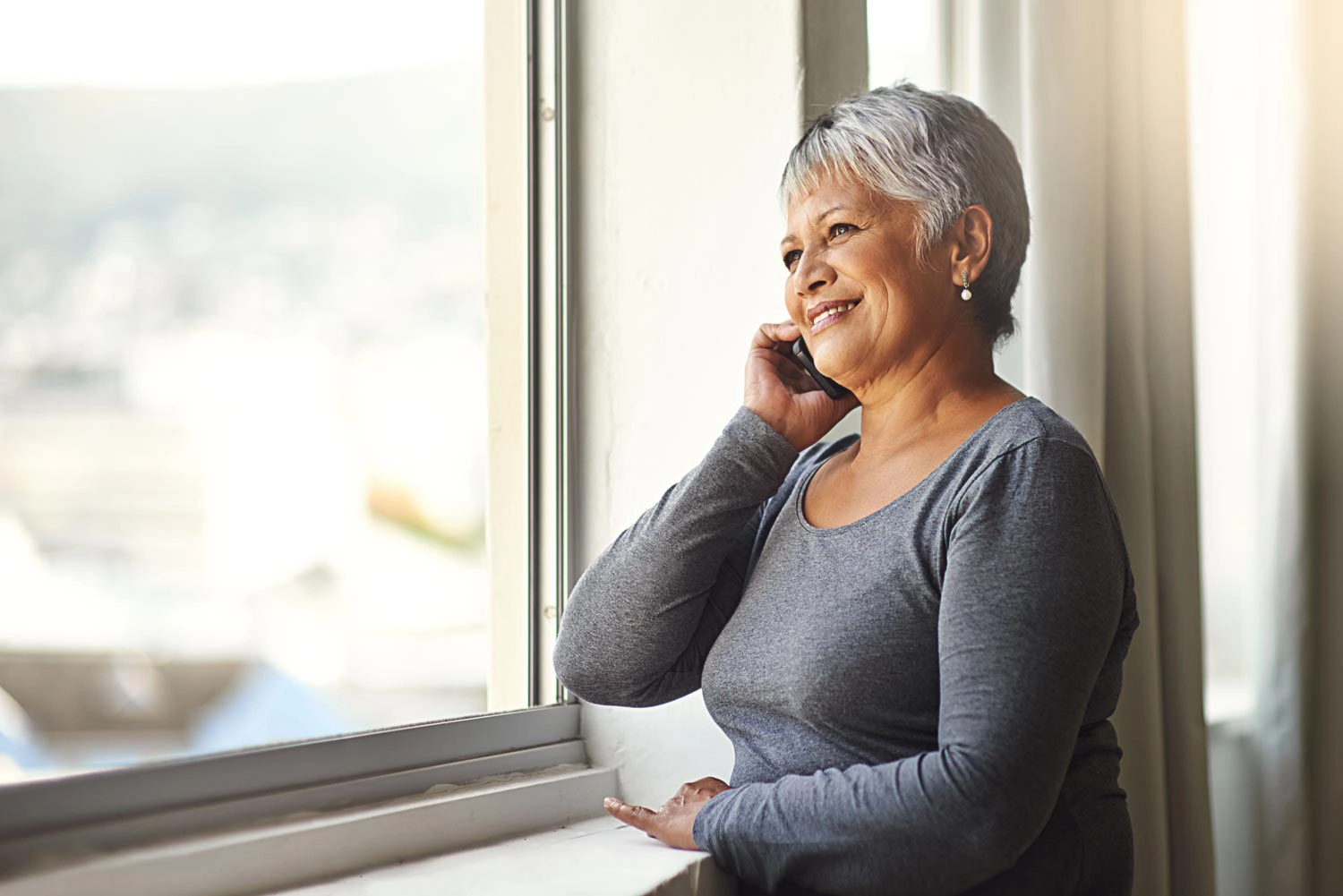 woman talks on phone by window