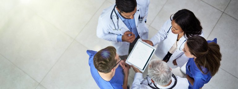 a group of medical researchers circle up around an ipad in a lobby