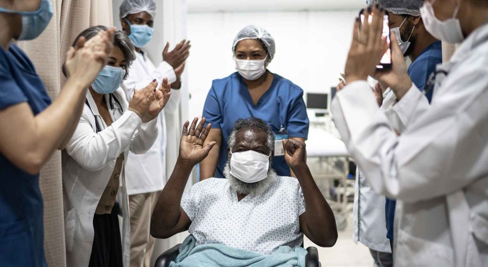 Hospital staff claps as African American senior in wheelchair is released