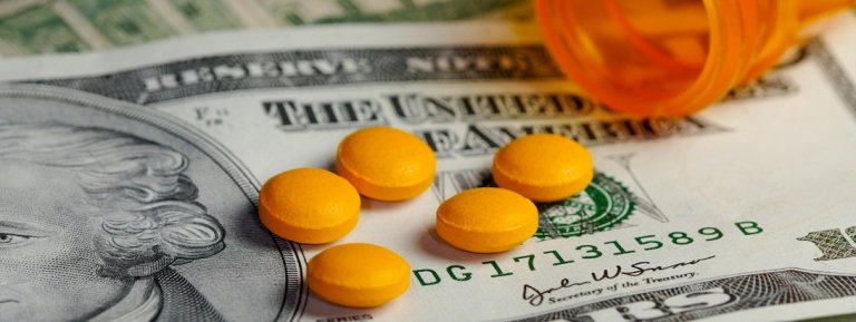 twenty dollar bill with open bottle of pills on top of it