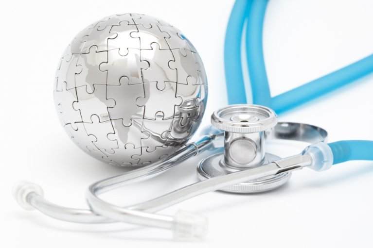 Silver dome made of puzzle pieces next to a blue stethoscope on a blue background