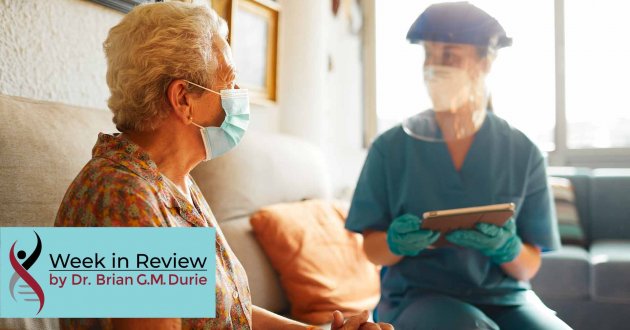 An elderly patient visits with a doctor equipped with full PPE protection