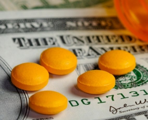 twenty dollar bill with open bottle of pills on top of it