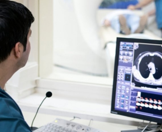 MRI technician looking at imaging scans on a computer screen