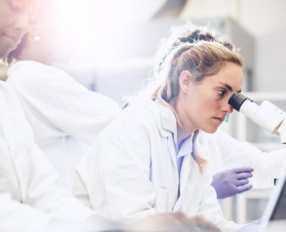 Researcher loos through a microscope.
