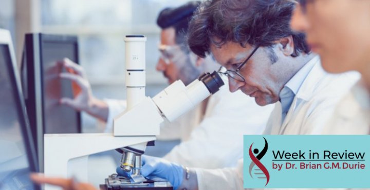 People in lab researching, looking at computer screens and microscope