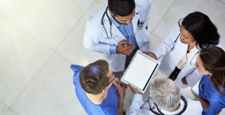 a group of medical researchers circle up around an ipad in a lobby