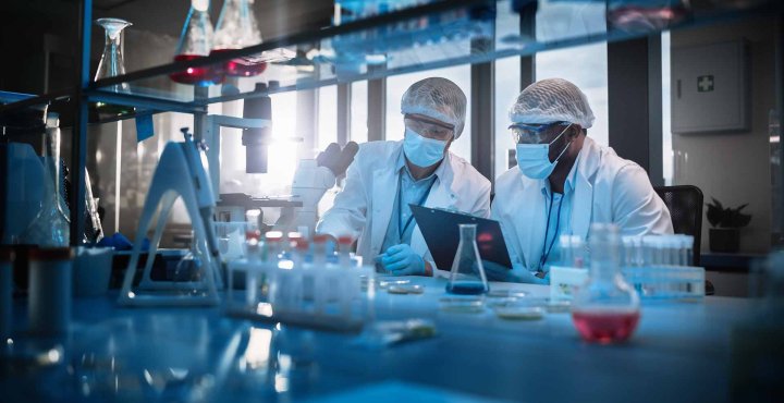 Two lab researchers analyze medical samples in protective gear