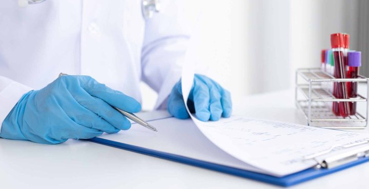 Scientist consults clipboard to analyze blood samples