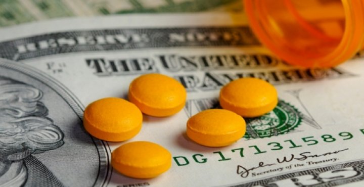 twenty dollar bill with open bottle of pills on top of it