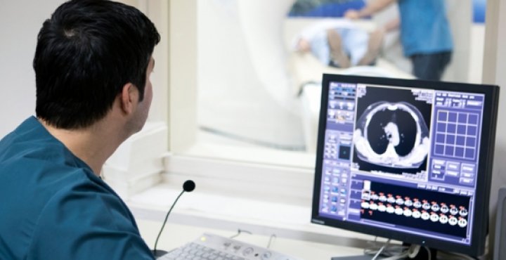 MRI technician looking at imaging scans on a computer screen