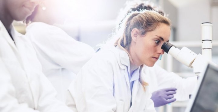 Researcher loos through a microscope.