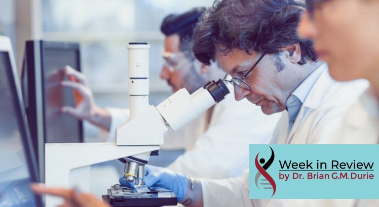 People in lab researching, looking at computer screens and microscope