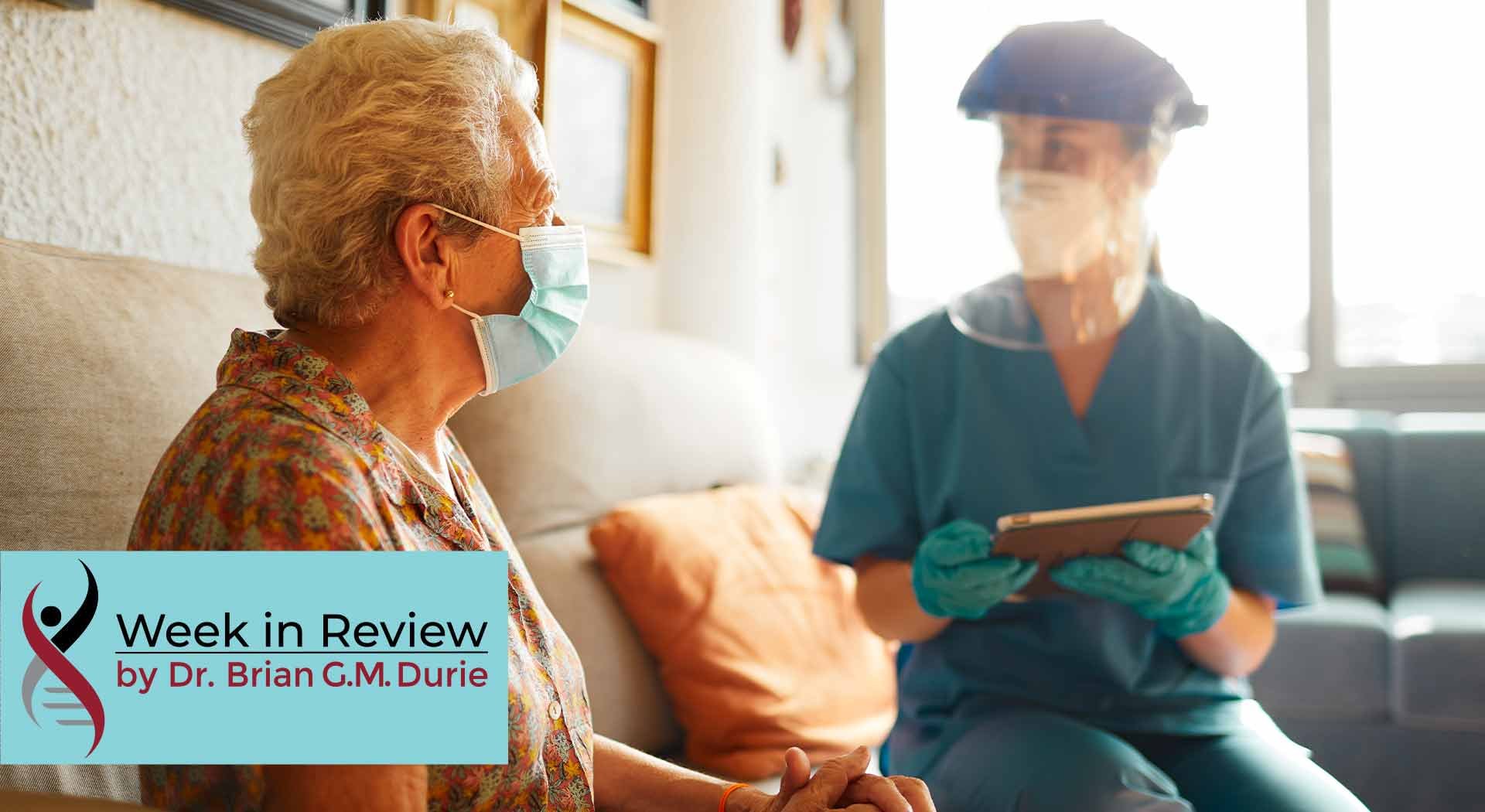An elderly patient visits with a doctor equipped with full PPE protection