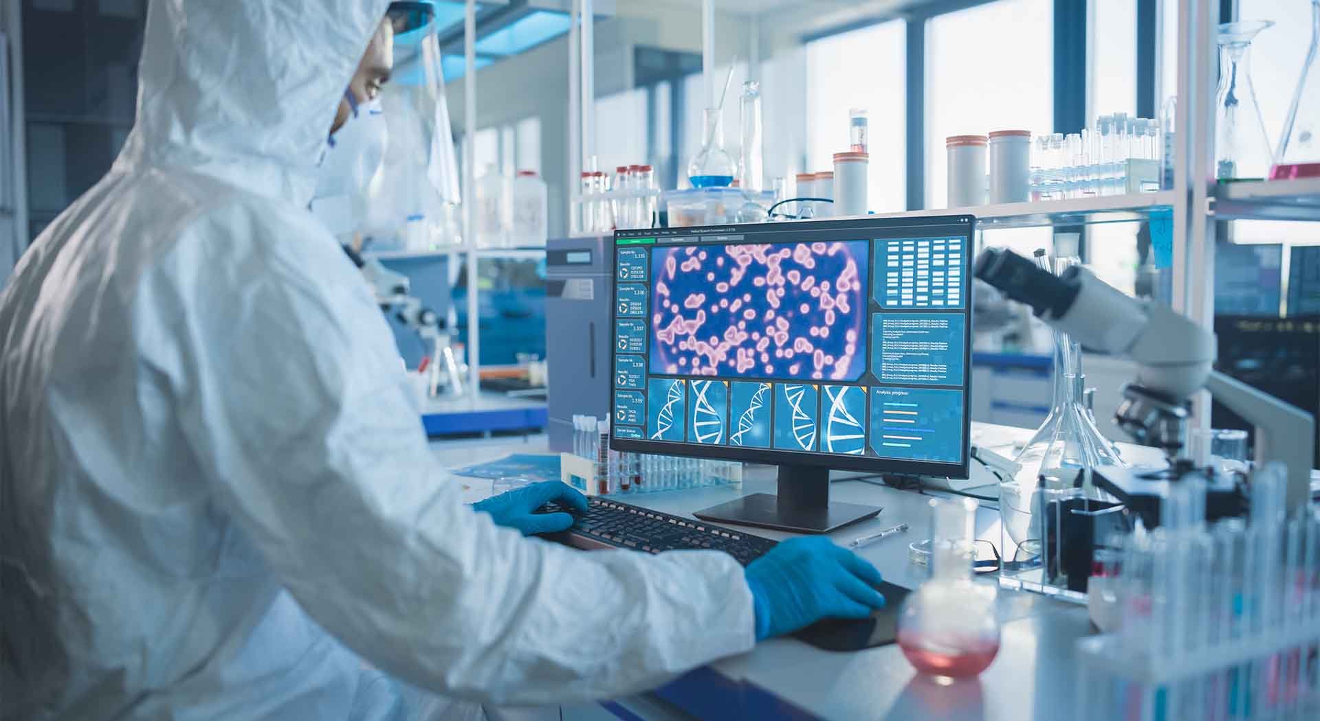 Masked scientist views research on lab computer