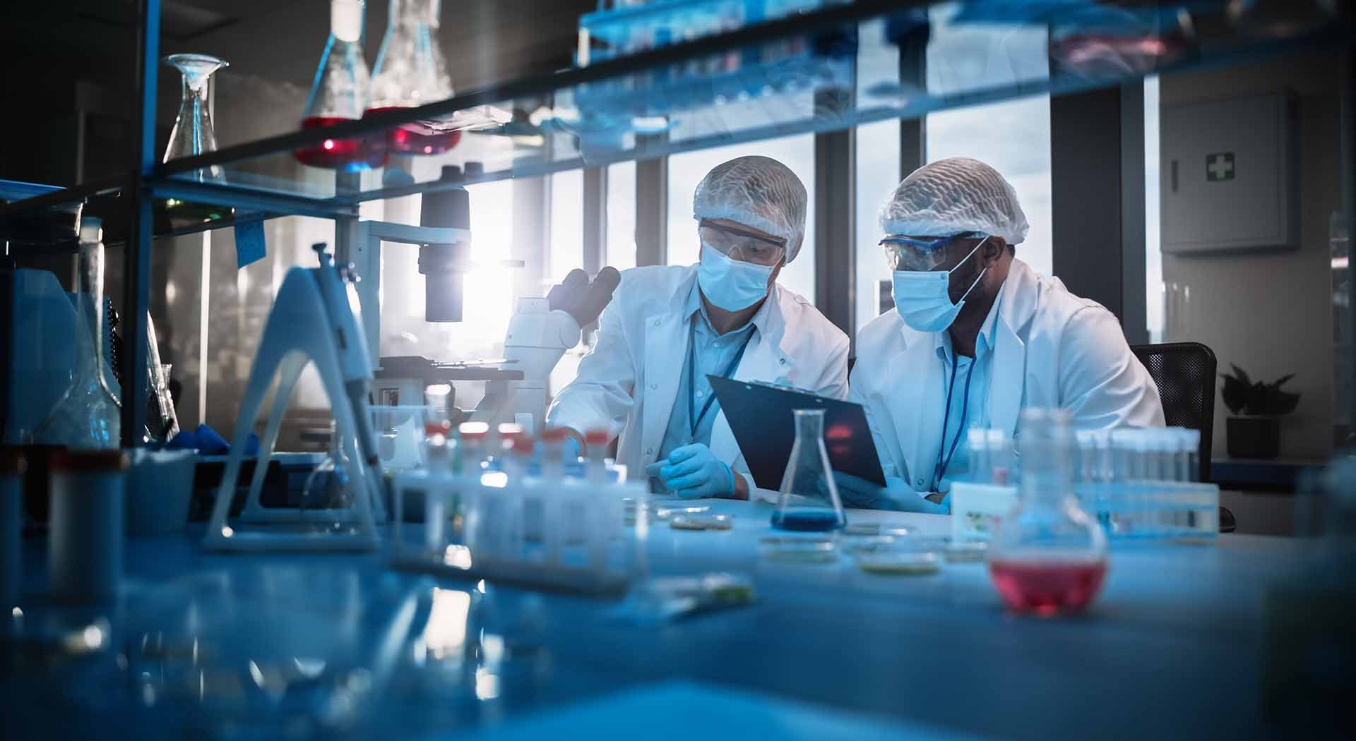 Two lab researchers analyze medical samples in protective gear