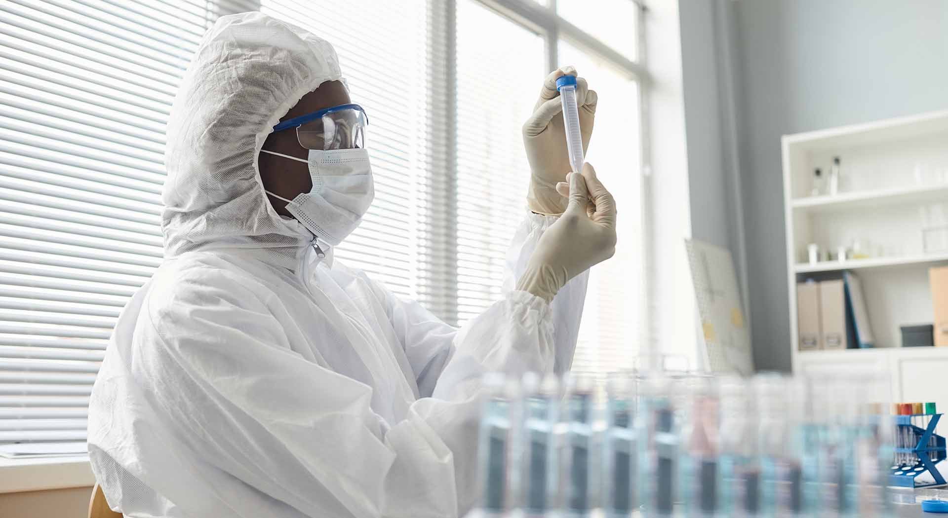 Scientist in lab wearing protective gear examines a sample