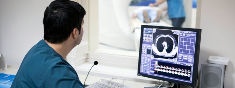 MRI technician looking at imaging scans on a computer screen