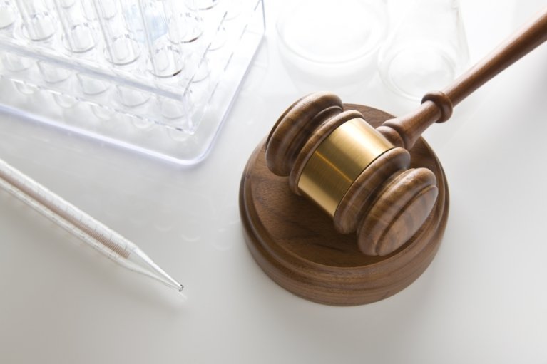 Judge's gavel along side medical research test tubes