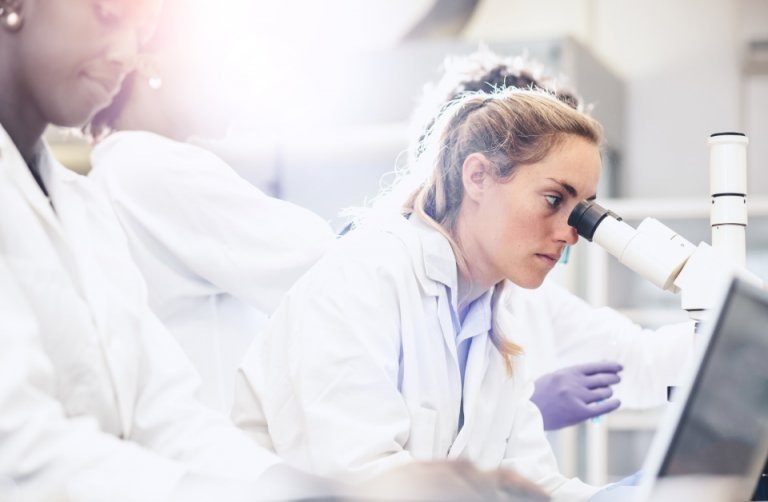 Researcher loos through a microscope.