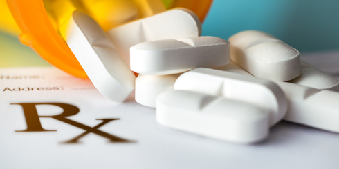 open pill prescription bottle with pills on prescription pad