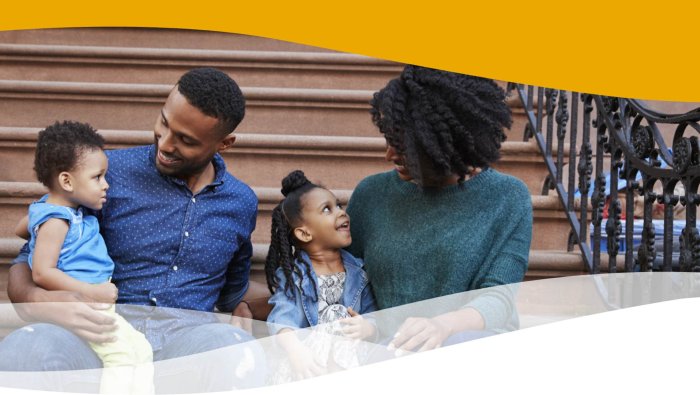 Black New Yorker family sits happily on apartment steps.